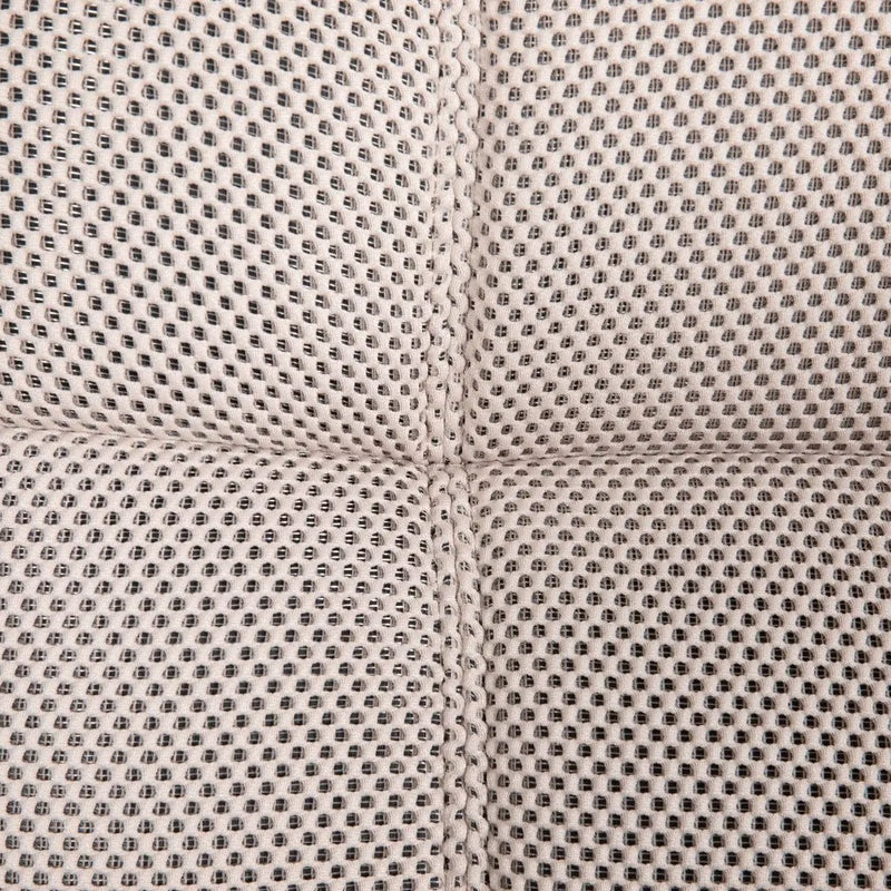 Close-up of a beige fabric with a dotted pattern and seams, showcasing the material of a sofa chair.