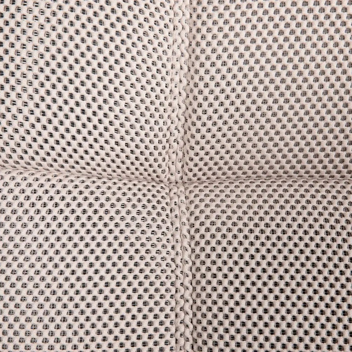 Close-up of a beige fabric with a dotted pattern and seams, showcasing the material of a sofa chair.