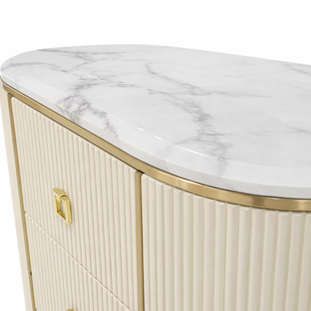 Close-up of a contemporary storage chest with cream ribbed drawers, gold trim, and a white marble top with grey veining.