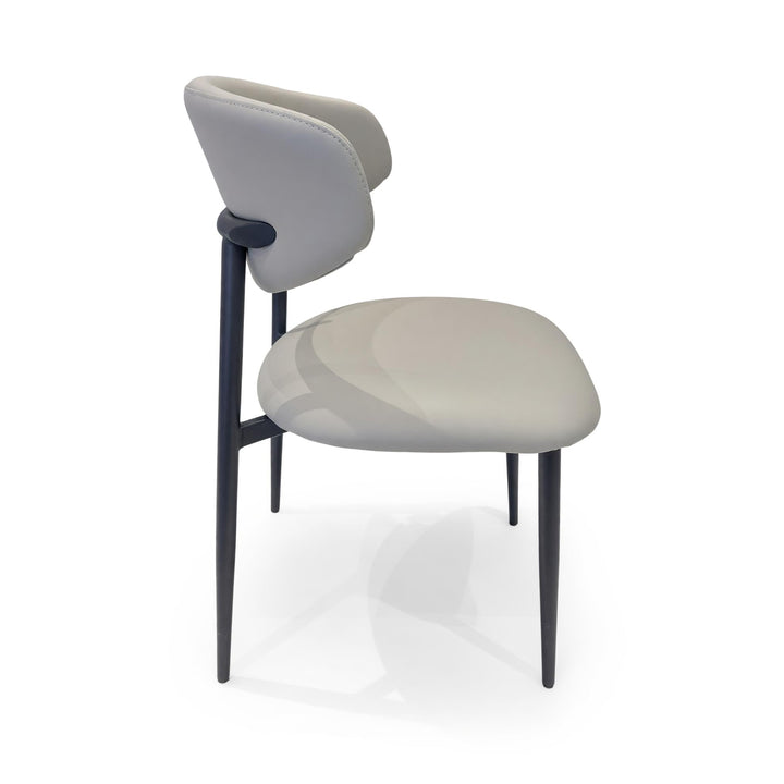 Minimalist dining chair with a curved, light grey upholstered back and seat supported by slender black legs.