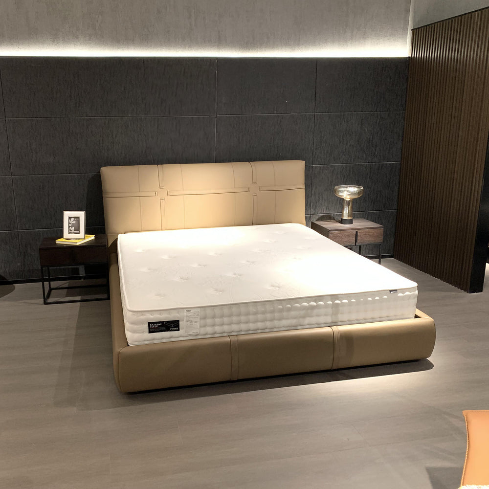 Low-profile beige upholstered platform bed with segmented headboard and white tufted mattress in a modern bedroom.