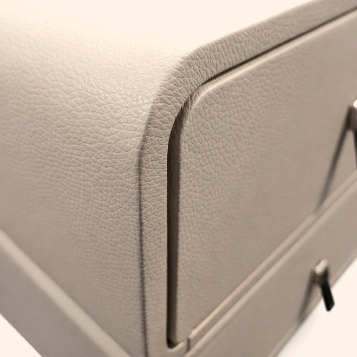 Close-up of a grey textured nightstand corner with silver metal drawer pulls.
