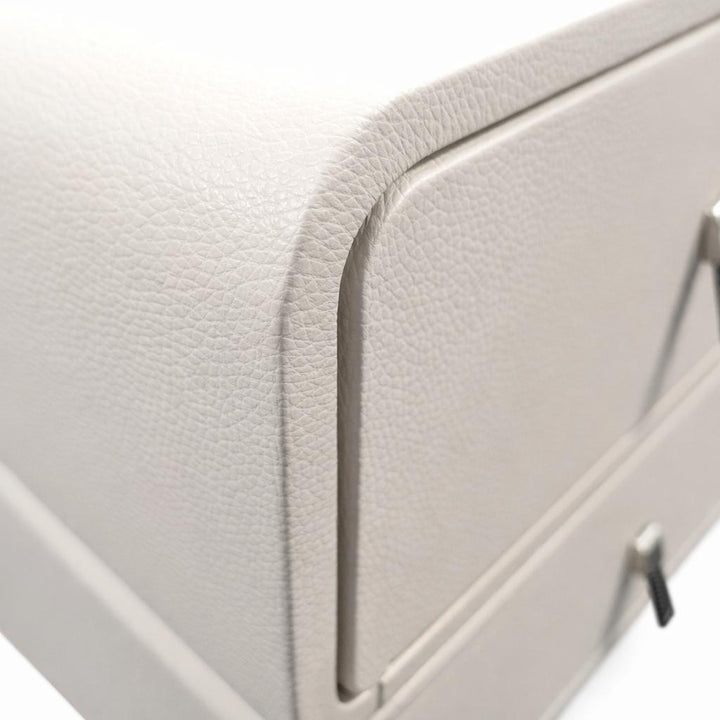 Close-up of a light grey nightstand with pebbled faux leather texture, rounded corners, and metal drawer pulls.