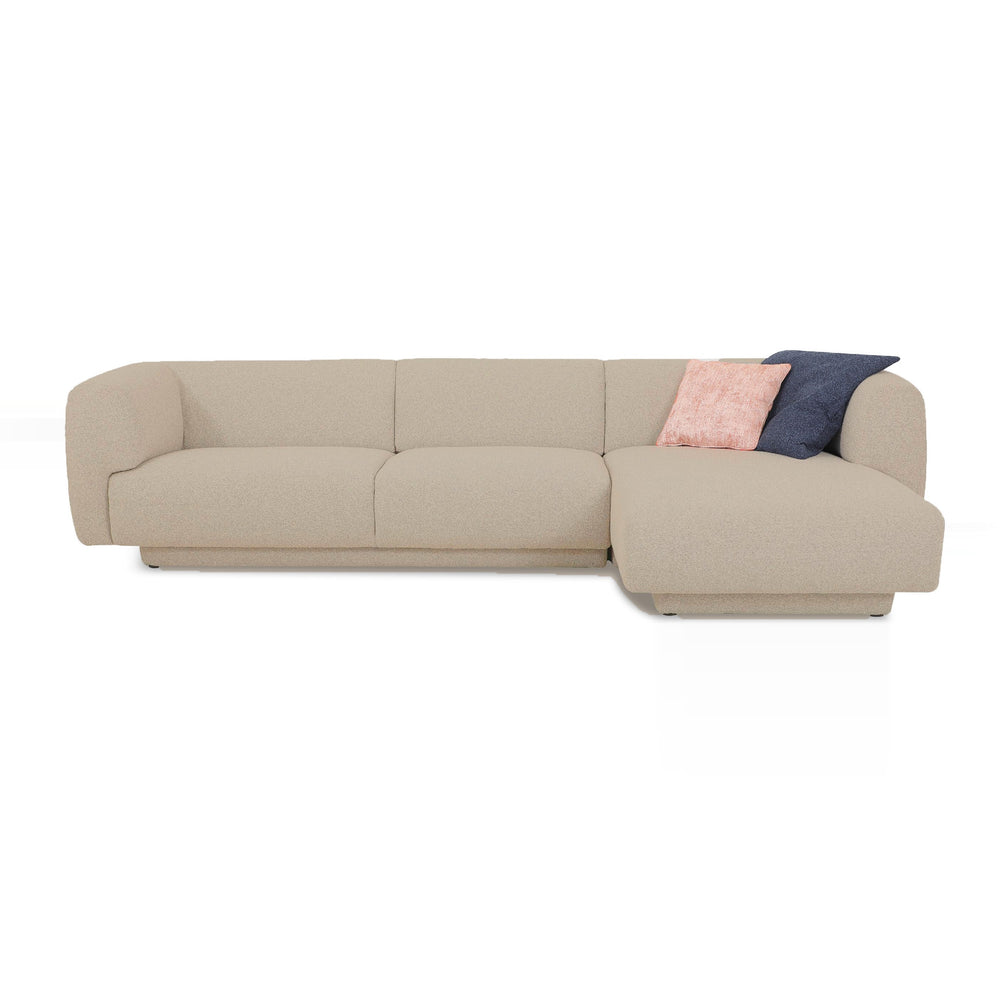 Oatmeal fabric sectional sofa with a right chaise, accented by a blush pink and navy blue throw pillow.