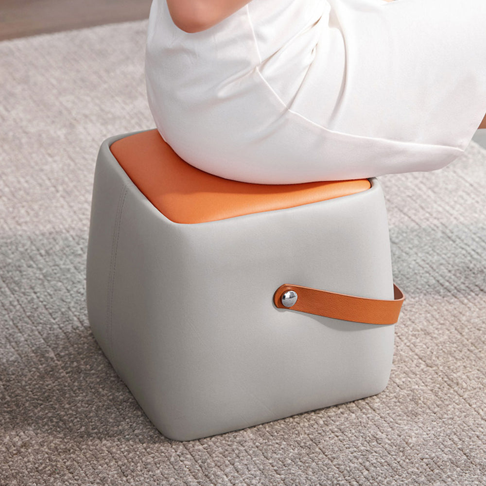 LINCOLN Versatile Foot Stool with a light grey body, orange cushion, and side handle, shown being sat upon.