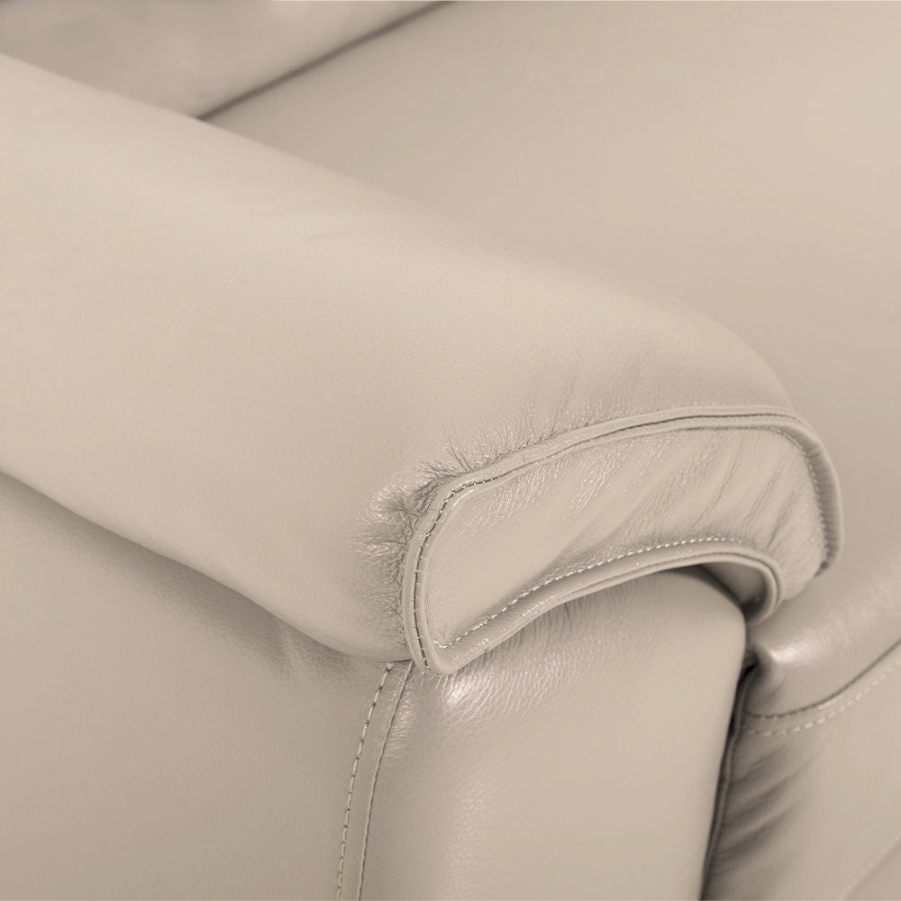 Close-up view of the cream-colored leather upholstery on the armrest of a sectional sofa, showcasing stitching details.