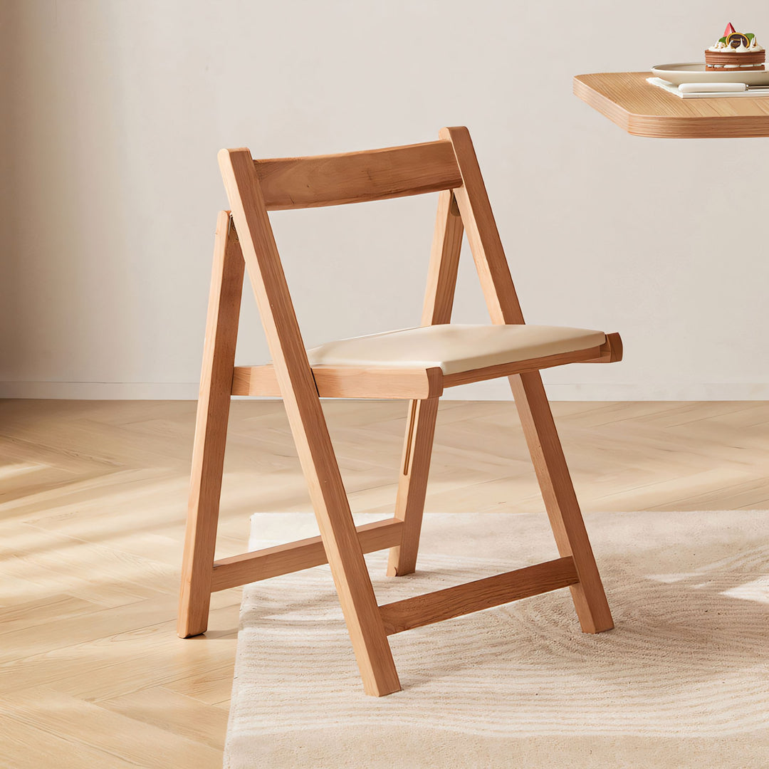 Natural wood folding chair with a cream upholstered seat and minimalist design.
