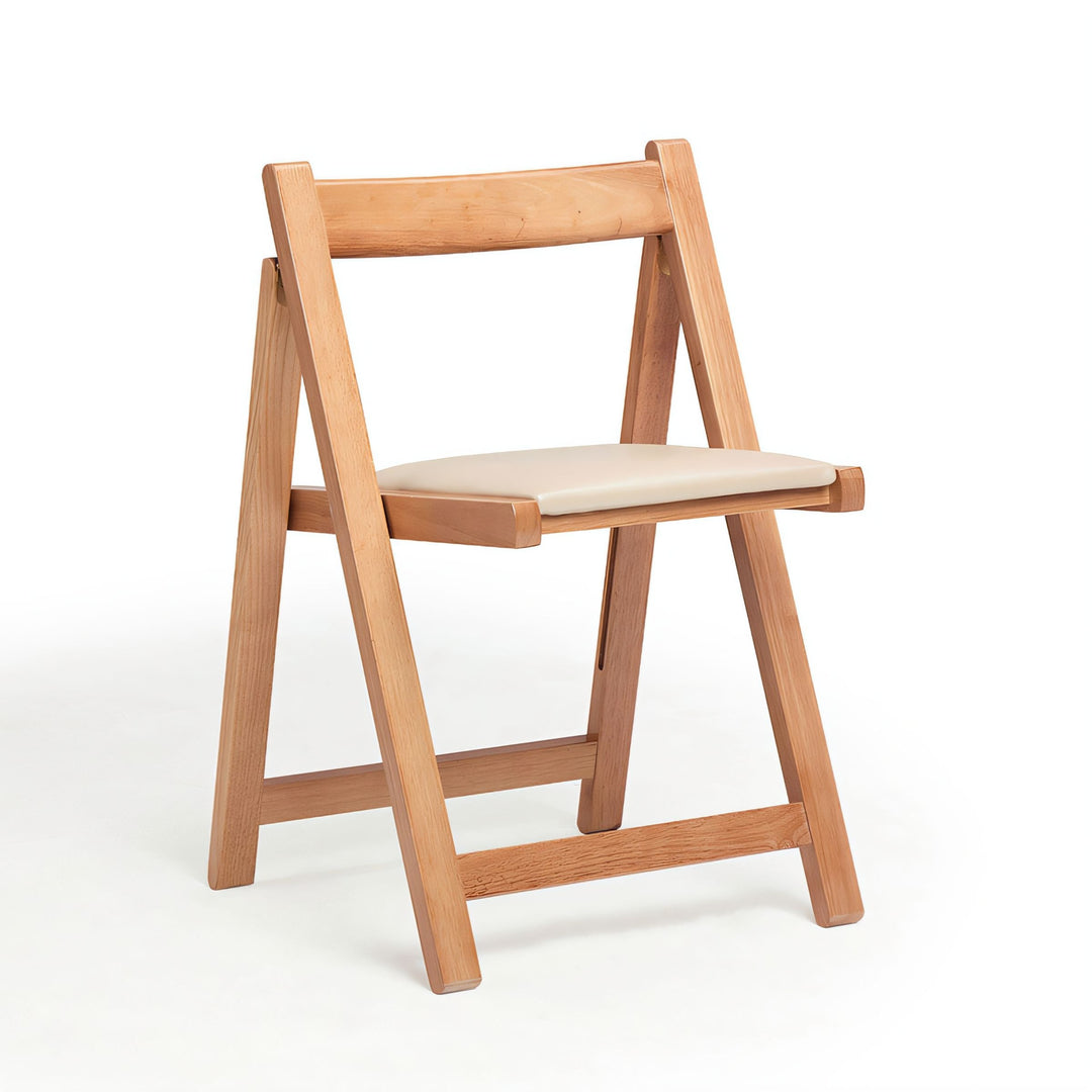 Light wood folding chair with a cream cushioned seat and minimalist X-frame design.