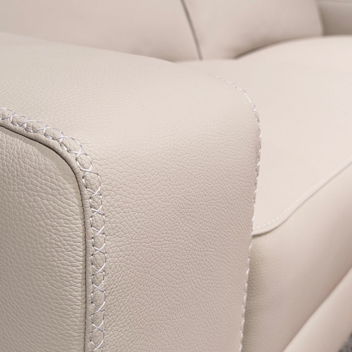 Close-up of a cream leather sofa armrest showing detailed stitching and texture.