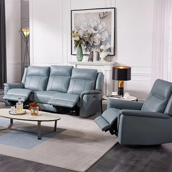 A 3-seater leather Frost sofa and a recliner in a living room setting. The furniture is blue-grey and placed against a backdrop of white walls, a painting, and decorative items, creating a modern and inviting room scene.