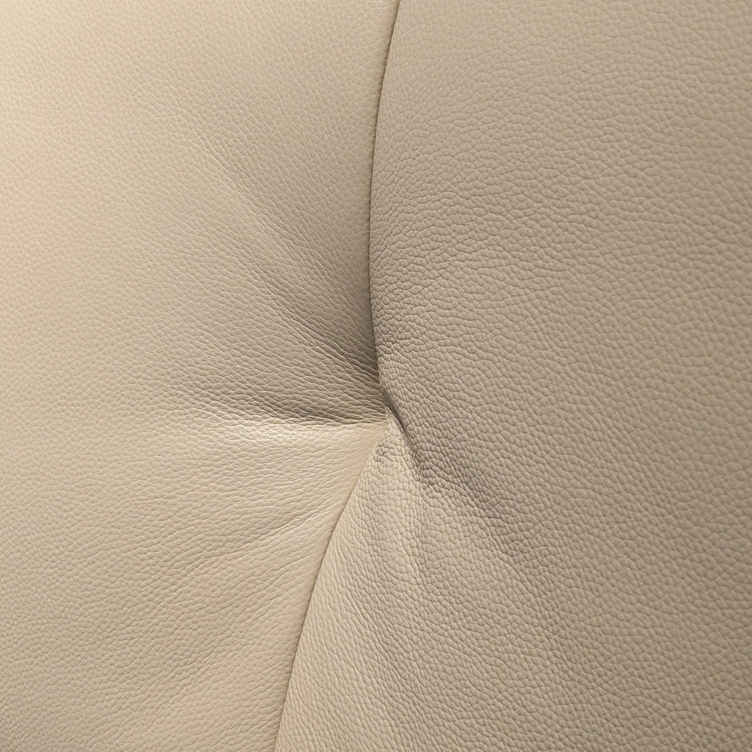 Close-up of beige leatherette material with a pebbled texture and a stitched seam.