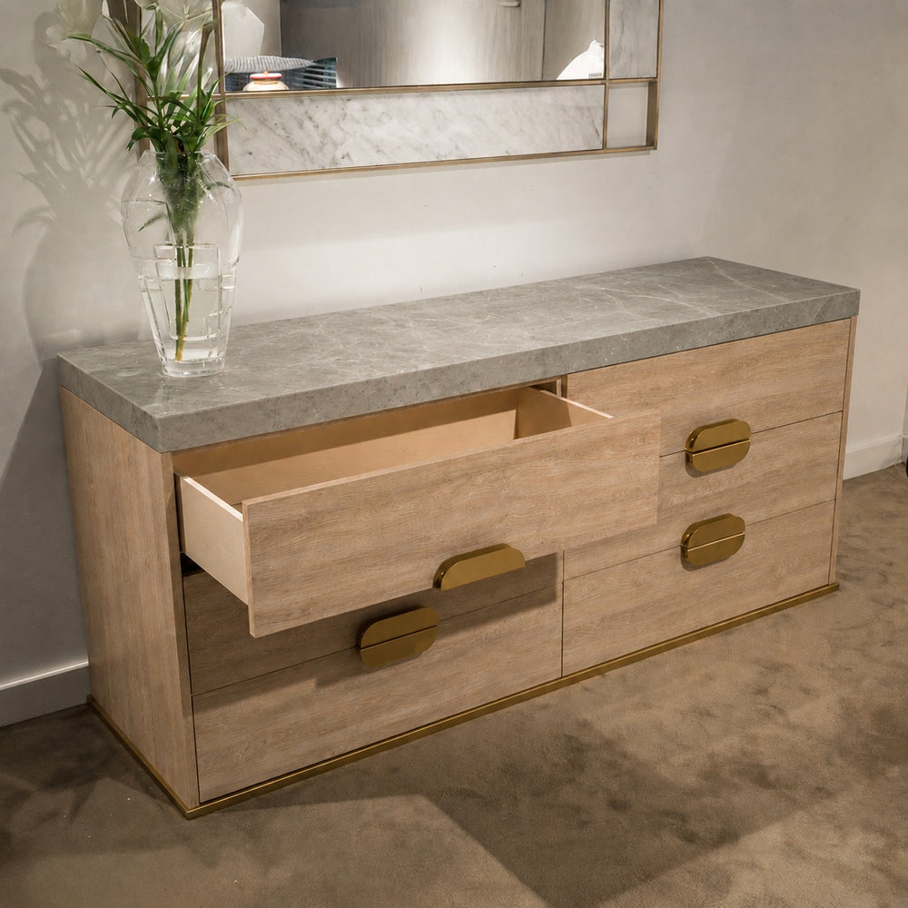 Grey wood dresser with white marble top and gold accents; one drawer open revealing light interior.