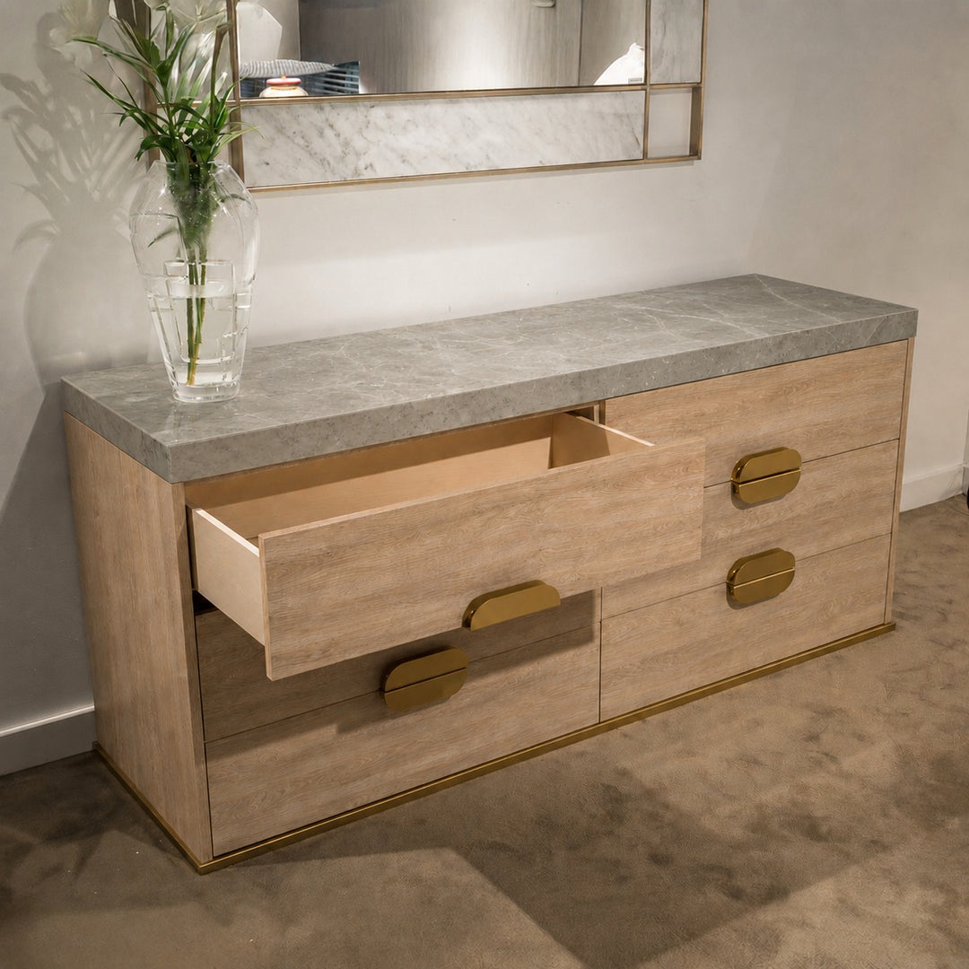 Grey wood dresser with white marble top and gold accents; one drawer open revealing light interior.
