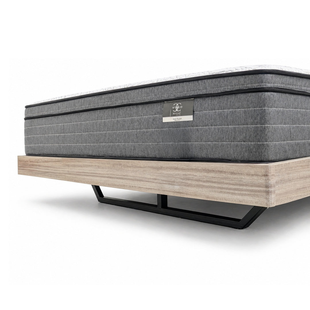 Grey mattress with horizontal stitching on a light wood platform bed frame with black metal legs.