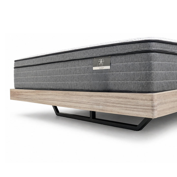 Grey mattress with horizontal stitching on a light wood platform bed frame with black metal legs.
