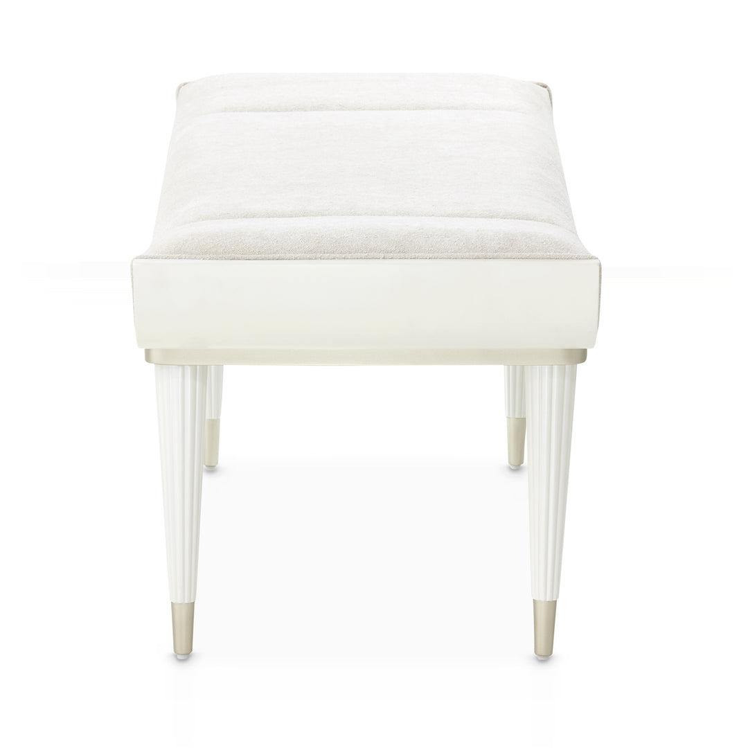 A white upholstered bench with fluted legs is isolated on a white background.