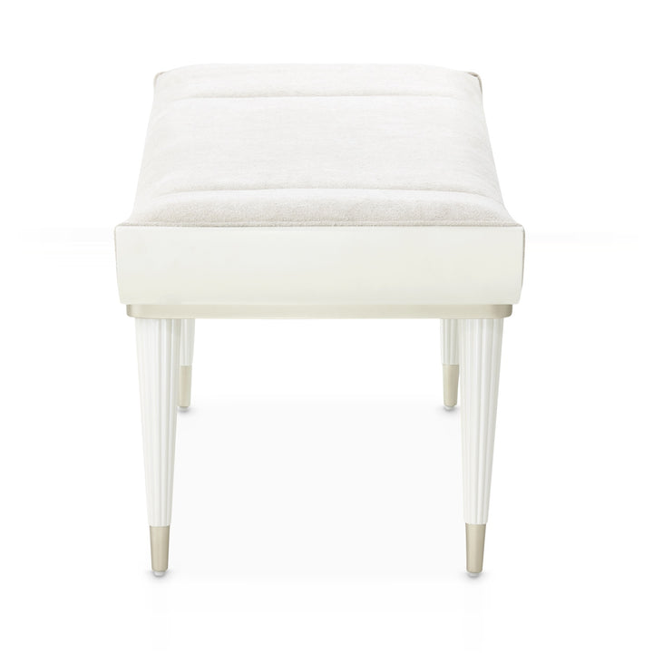A white upholstered bench with fluted legs is isolated on a white background.