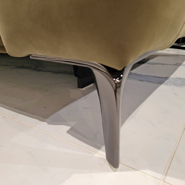 Close-up of a furniture leg showcasing its chrome finish and attachment to a beige upholstered piece, highlighting material details.