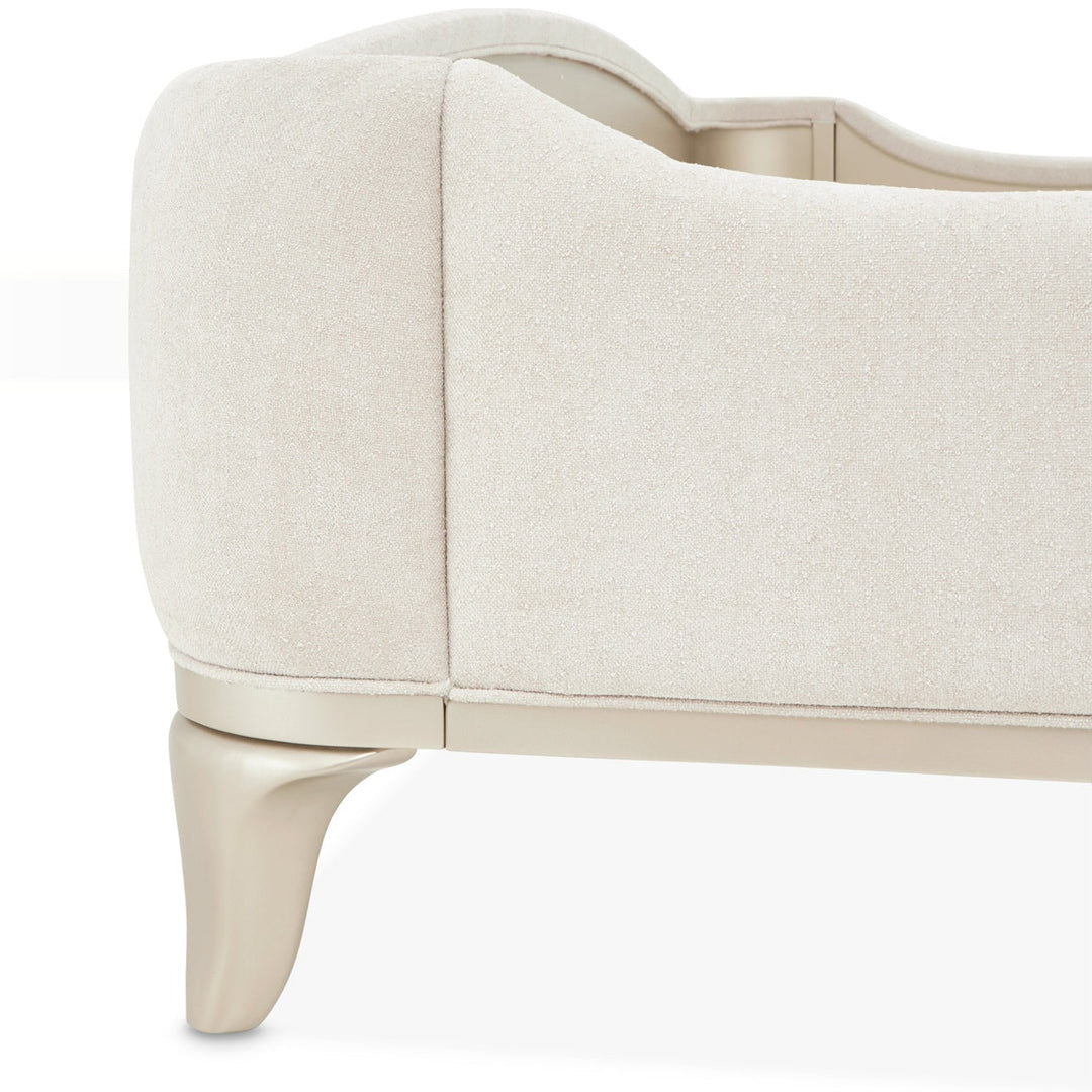 Close-up of a cream-colored chair or bed with unique leg design on a white background.