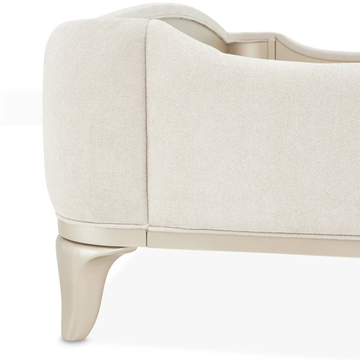 Close-up of a cream-colored chair or bed with unique leg design on a white background.