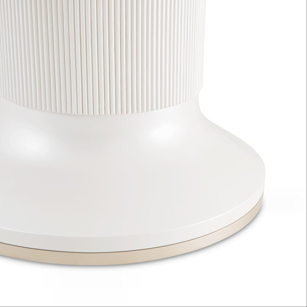 Close-up of a white side table with a ribbed top and gold accent, isolated on a white background.