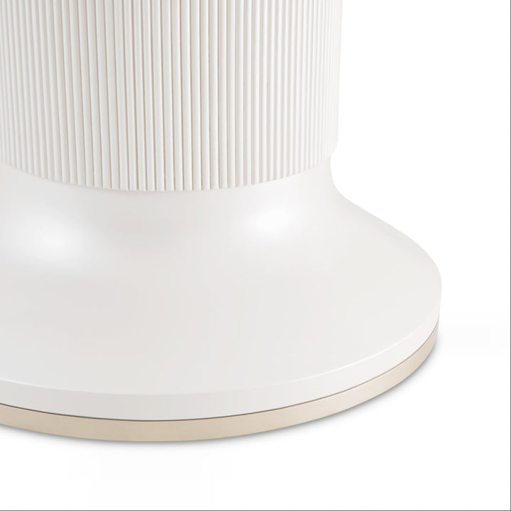 Close-up of a white side table with a ribbed top and gold accent, isolated on a white background.