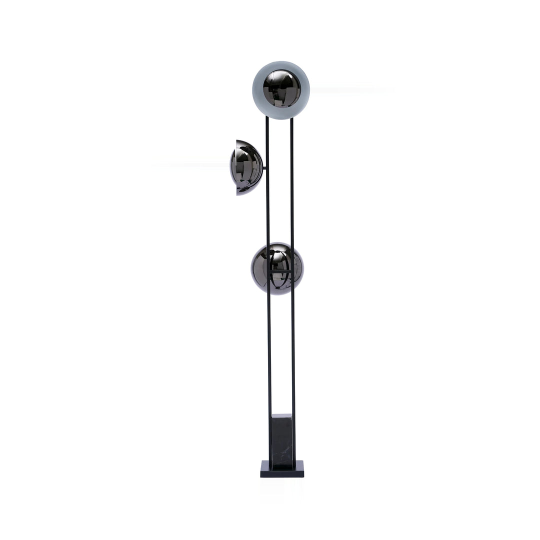 A modern floor lamp with black metal frame, three spherical lampshades in chrome, and a square black marble base, isolated on a white background.
