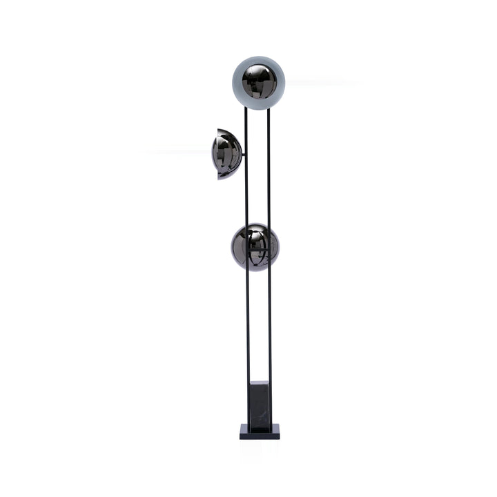 A modern floor lamp with black metal frame, three spherical lampshades in chrome, and a square black marble base, isolated on a white background.