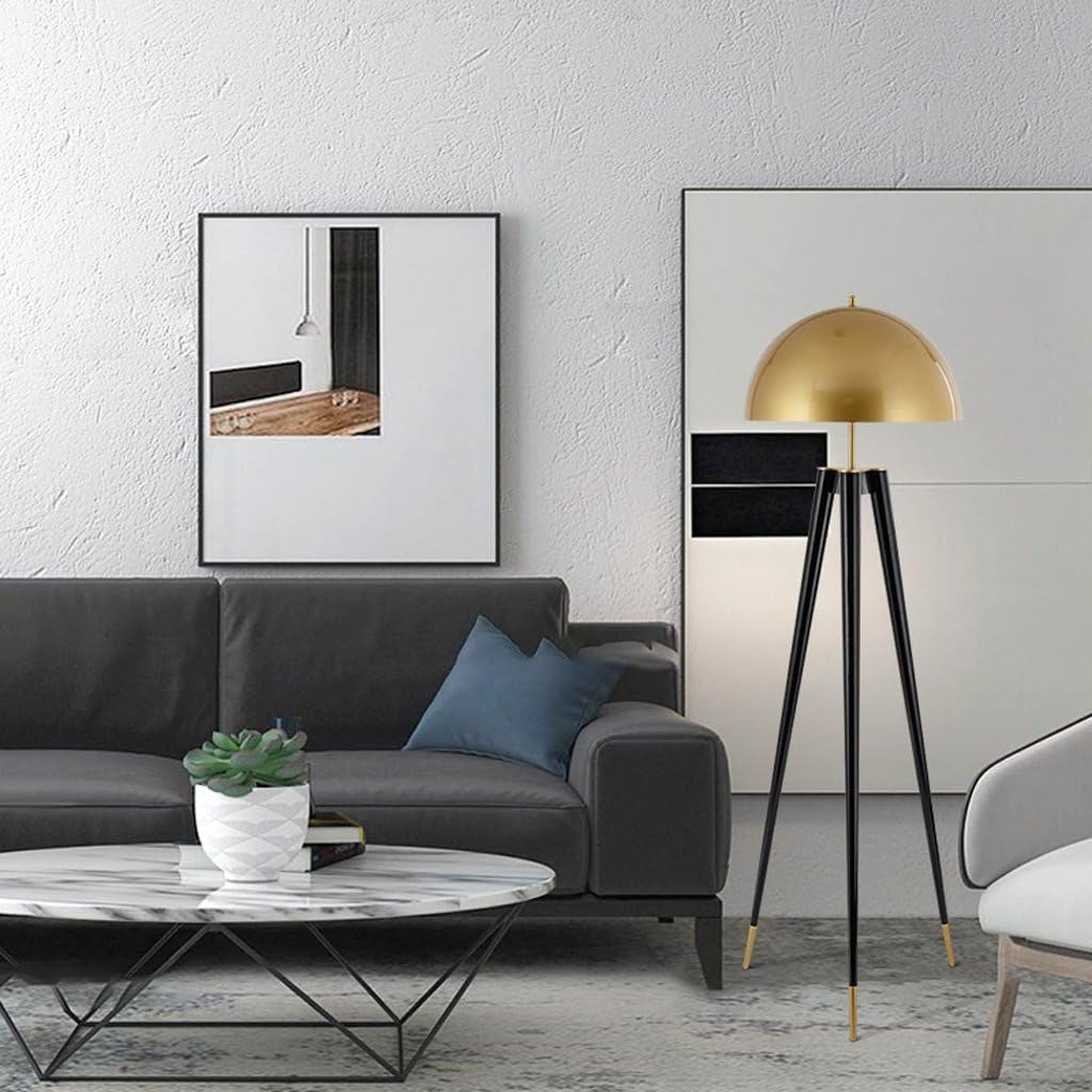 Living room scene featuring a black sofa, marble coffee table, art on the wall, and a gold and black tripod floor lamp.