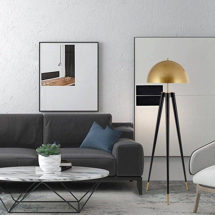 Living room scene featuring a black sofa, marble coffee table, art on the wall, and a gold and black tripod floor lamp.