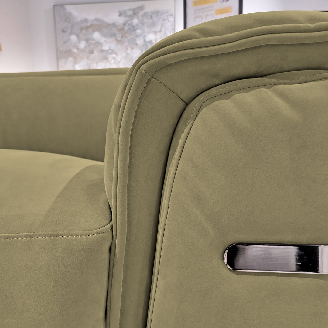 Close-up of a light green velvet armchair in a room setting, showcasing the armrest detailing with visible seams and a silver metallic accent.