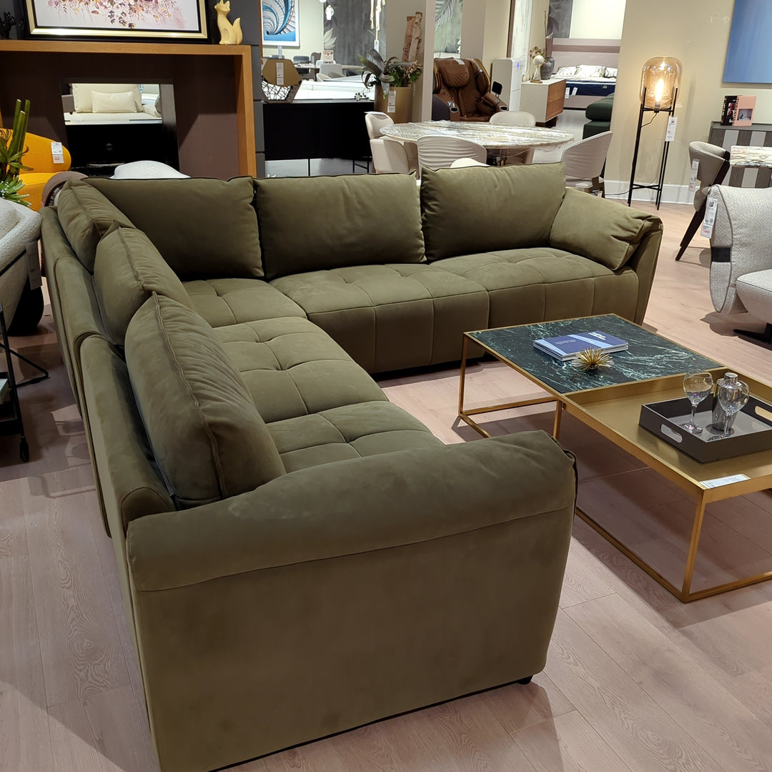 A living room scene featuring an olive green sectional sofa and coffee tables with gold frames.