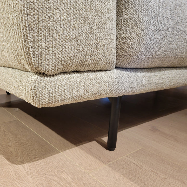 Close-up shot of a sofa's textured fabric and metal legs, showcasing material details and construction.