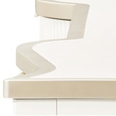 Close-up view of a furniture detail showing the edge and material finish, possibly a countertop or tabletop, with a cream-colored edge and a white top.