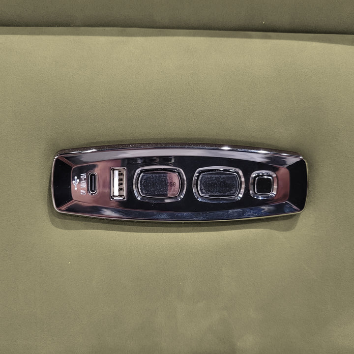 Close-up of a furniture control panel with USB ports and buttons, set against a green fabric background.