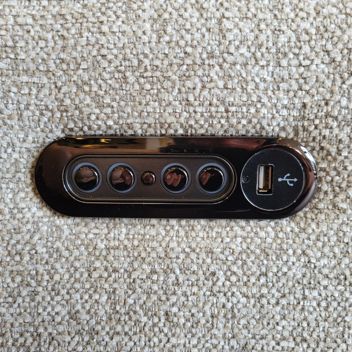 Close up of a black control panel with buttons and a USB port, set against a textured beige fabric background.