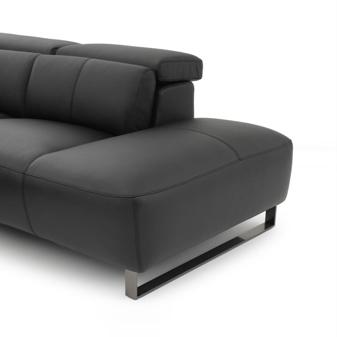 Close-up of a modern black leather sofa with adjustable headrests and metal legs, presented against a clean white background.