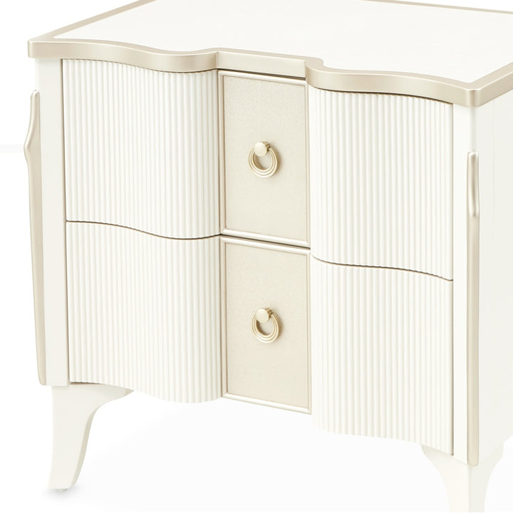 Close-up of a white and gold nightstand with two drawers and ring pulls on a white background.