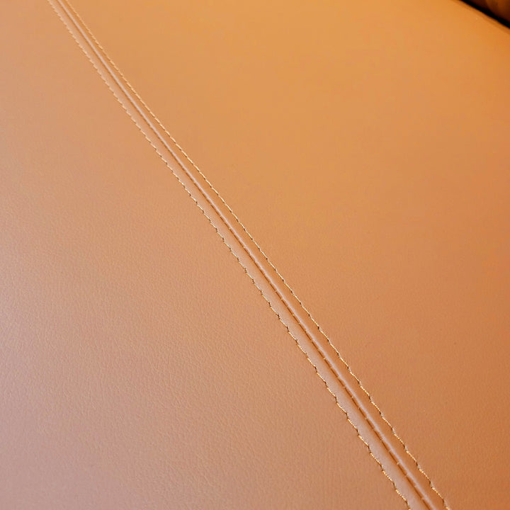 Close-up of brown leather with decorative stitching.