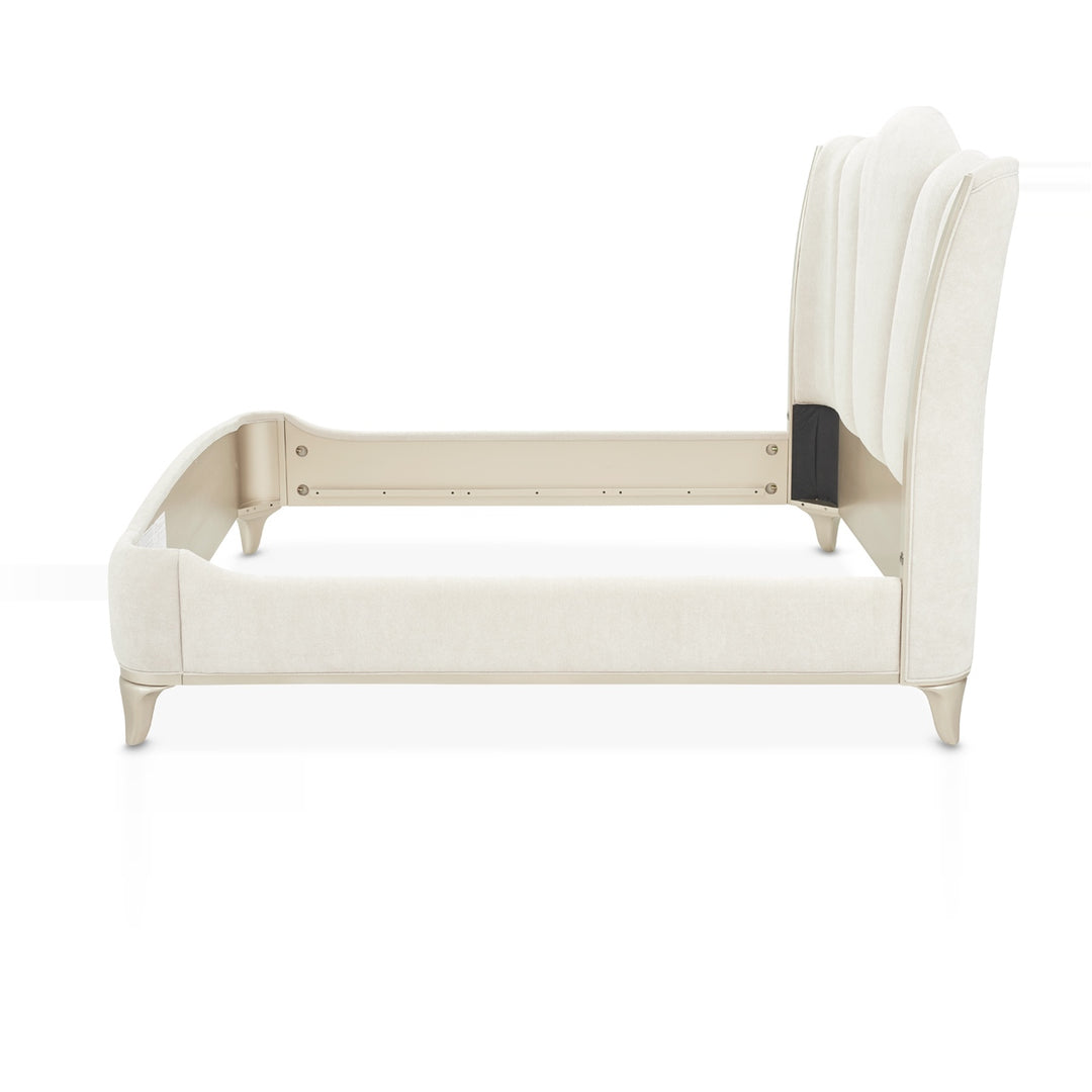 Side view of a luxurious white upholstered bed frame with a tall, curved headboard and silver legs, set against a plain white background.