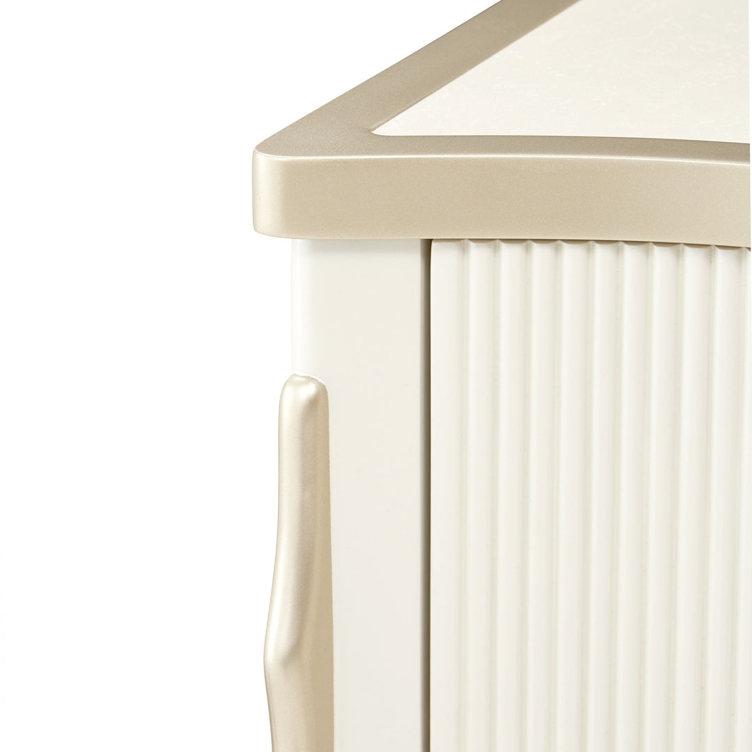 Close-up of a white and gold furniture piece on a white background, featuring vertical grooves, a metallic handle, and a contrasting gold trim on the top edge.