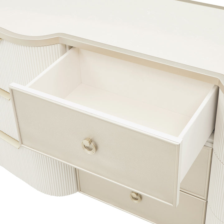 Close-up of a white dresser with one drawer open, showcasing its ridged detailing and circular drawer pulls, set against a neutral background.