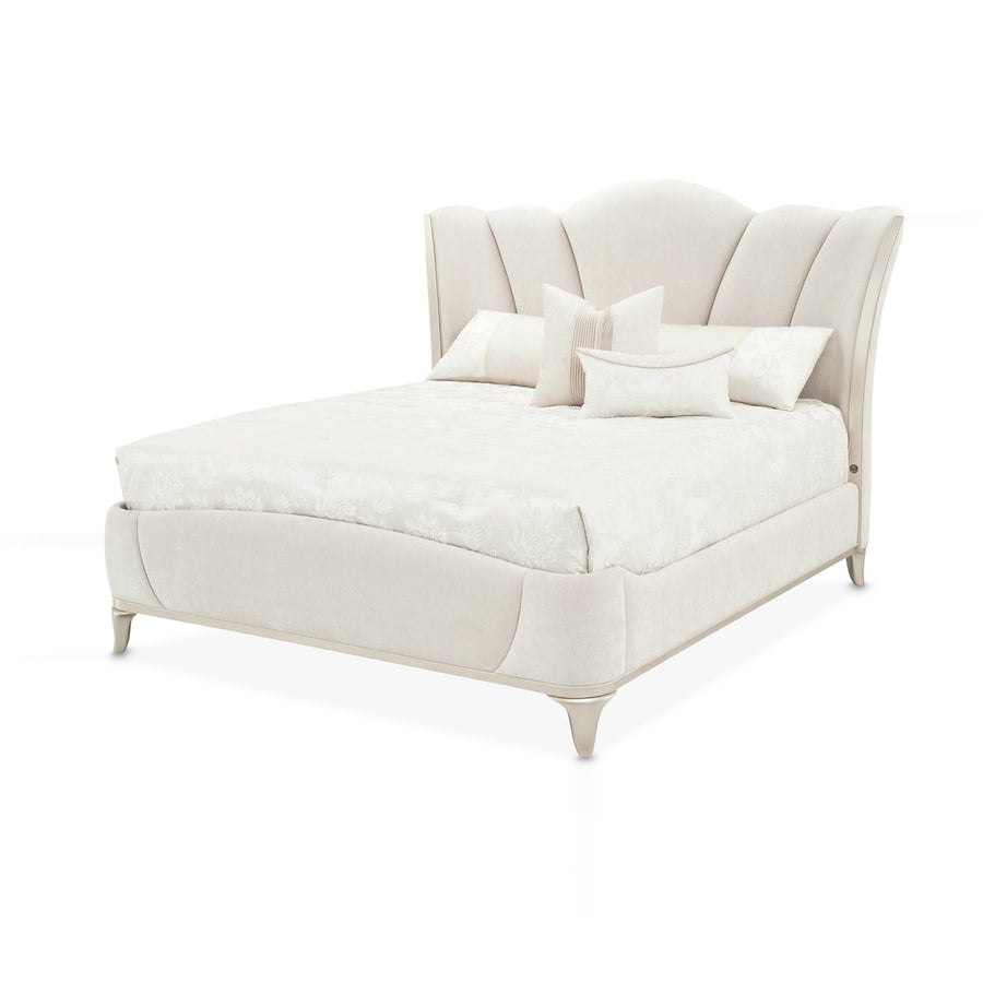An upholstered bed with an ornate headboard and decorative pillows is displayed on a white background.