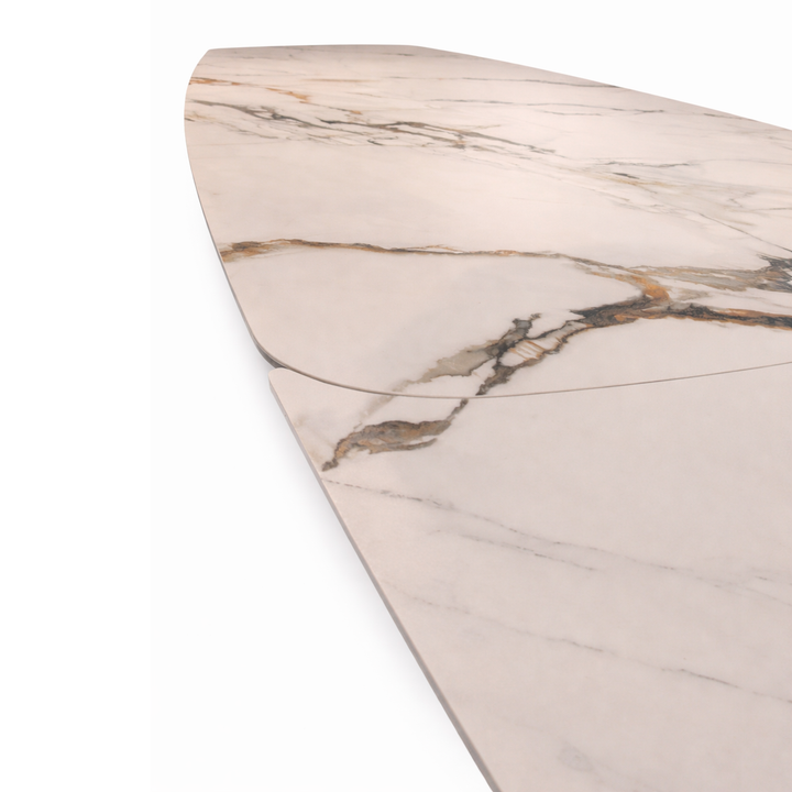 Close-up of a white marble table top with gold and grey veining and a visible extension seam.